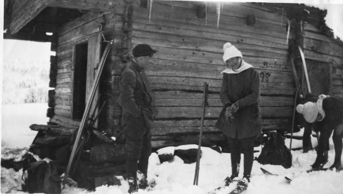 En ung mann står sammen med to unge kvinner som tar på seg ski foran en støl på Fjellberg, i Suldal.