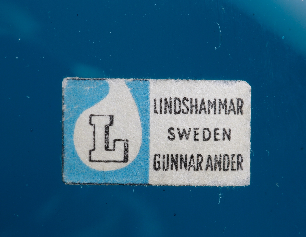 Spargris. Kupan (kroppen) päronformad. Kort hals, rak krage (nosen). Rektangulär etikett med ett "L" inom en bubbla på blå botten samt text.

Inskrivet i huvudkatalogen 1964.