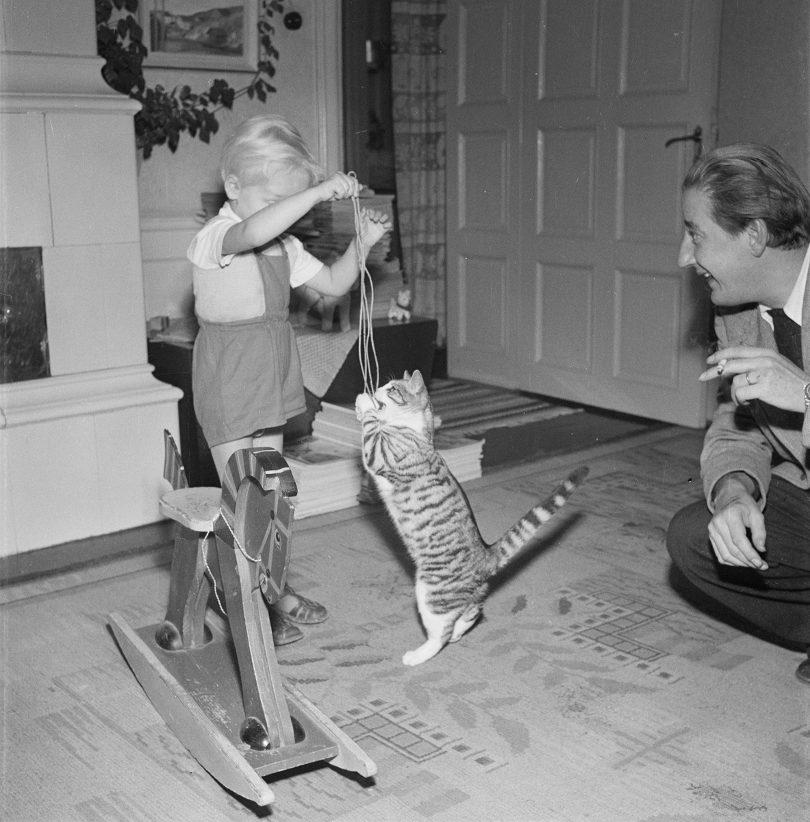 Redaktör Hugo Wortzelius med son leker med katt, Uppsala 1954