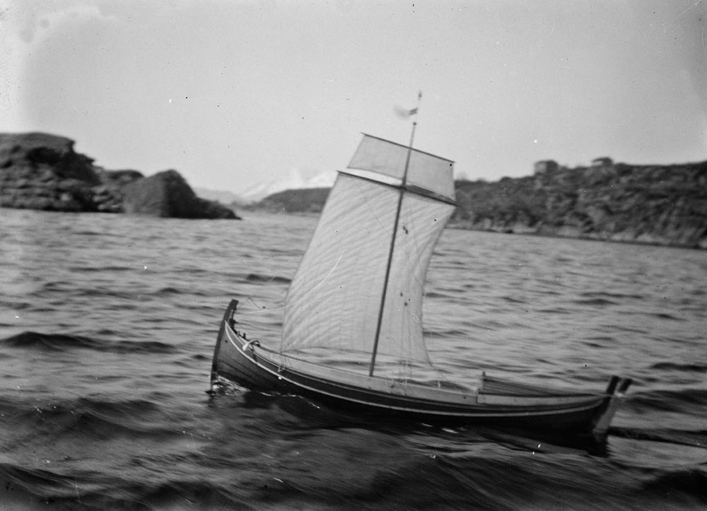 Leirfjord, Ulvangen, Myrvang. Kornelius Myrvang sin modell av en fembøring prøveseiler like øst for Meisfjordholmen. Under prøveseilingen seilte den visstnok fra følgebåten.