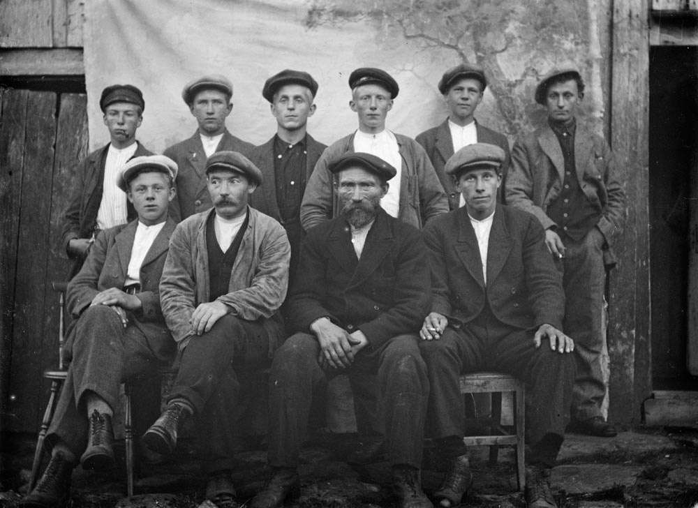 Leirfjord, Ulvangen. Gruppebilde av et notlag fra Ulvangen.
F.f.v.: Jan Mortensen, Hans Larsen, Reines, Anders Jørgen Nicolaisen, Ulvang og Ingbart Salamonsen.
B.f.v.:  Noranus Andersen, Ulvangen, Magnus Benjaminsen, Ulvangen, Johan N. Angersnes, Einar Hartvigsen, Vidar Olsen og Sverre Zahl Reines. 
Karene har på seg ulike typer dresser og alle har hodeplagg på. Sixpence og karsjettlue. De står og sitter på stoler foran bakteppet som Kornelius (fotograf) ofte brukte. Bildet er tatt ute.