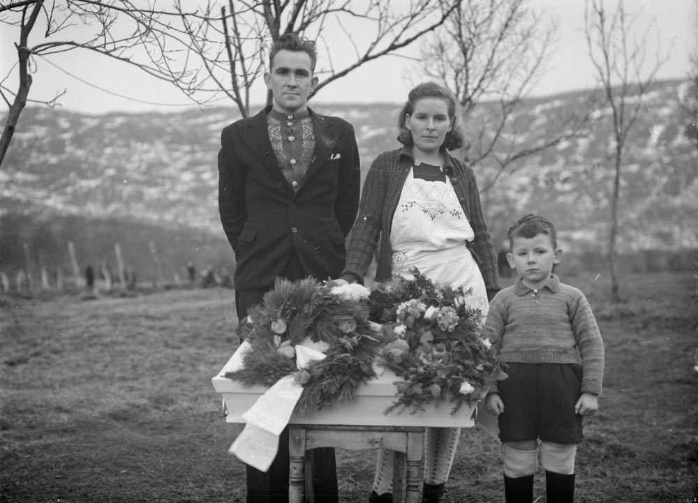 Leirfjord, Ulvangen, Myrvang. Begravelsen til Oddrun Myrvang som døde 6 måneder gammel, i 1946. Hun ligger begravet på Meisfjord kirkegård, ved gjerdet på nord-vest siden. Bildet er tatt utenfor huset på Myrvang. F.v.: Arthur Myrvang, Aslaug Myrvang og Dagfinn Myrvang. Arthur og Aslaug fikk to sønner og en datter som vokste opp. Arthur er bror til fotografen.