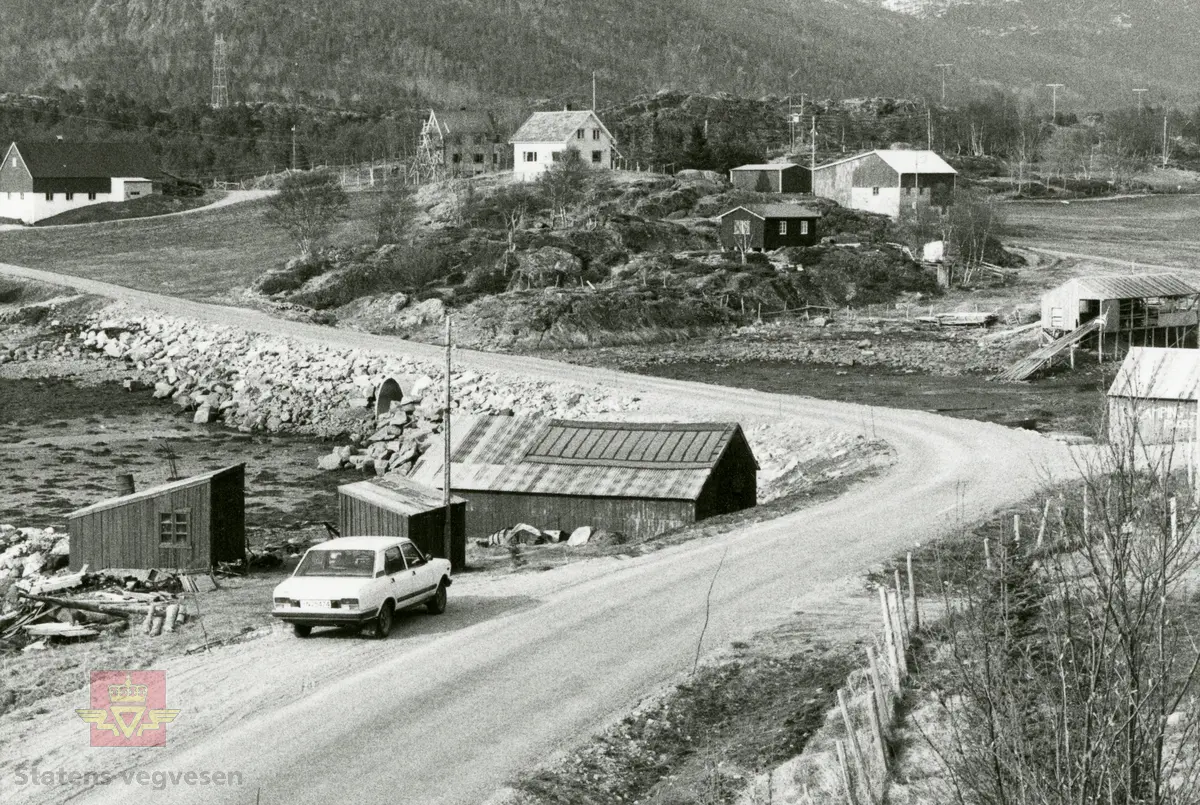 Veg som går mellom naust og bebyggelse. Sted: Kobbvika i Efjord. 
Vegen har Ottadekke. På bildet en 1977 modell Fiat 2000.