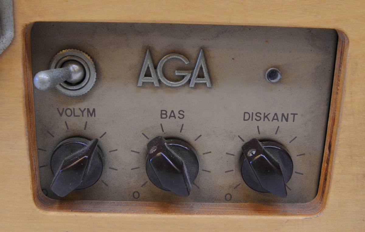Resegrammofon tillverkad av Almqvist & Wiksell under 1960-talets första år. Grammofonen är av väskmodell med rektangulärt kabinett i ljus plywood med bärhandtag i brun bakelit. Undersidan av kabinettet har luftningsslitsar urfrästa i plywooden. I det avtagbara locket finns en högtalare bakom grått tyg. 

Skivspelaren är remdriven och placerad till höger i kabinettet samt har ett chassi av gråmålad plåt med rundade kanter. Armen är av svart bakelit som hålls på plats med ett enkelt spänne vid transport och bredvid armen finns ett svart bakelitvred för inställning av uppspelningshastigheten. Skivtallriken är av metall och har en matta av grått gummi.

Till vänster om skivspelaren finns förstärkardelen som är rördriven och har ett ventilerat chassi i gråmålad plåt. Reglagen är åtkomliga från kabinettets framsida och består av en vippströmbrytare samt tre vred i brun bakelit för volym, bas och diskant. Över vreden finns AGA:s logotyp. Till vänster om förstärkaren finns ett fack för ström- och högtalarkabel.