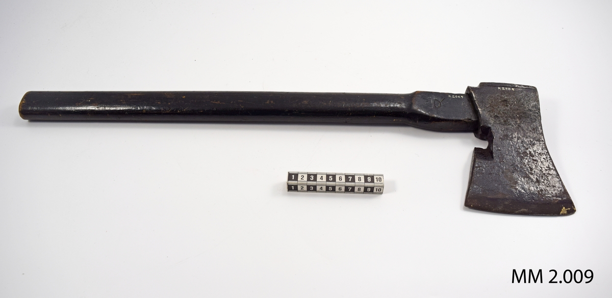 Yxa av stål med träskaft, svartmålad. Såväl yxa som skaft med tre kronstämplar. På skaftets ände en mässingsbricka med nr 524, troligen timlönarens nummer. Härstammar från 1800-talets senare del och har använts av timlönare på örlogsvarvet.