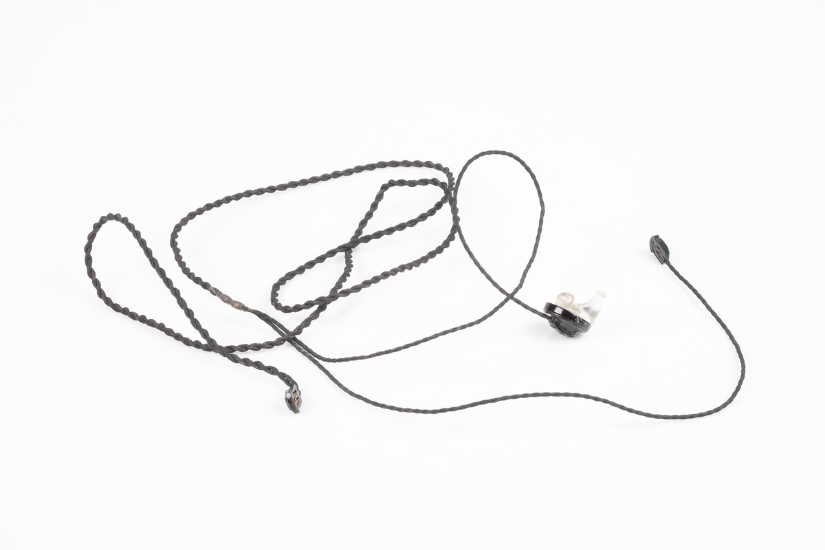 Ørepropper som kobles til radioen. Den har svart flettet ledning og propp i plast som kan fjernes fra ledningen. Den ene proppen mangler.