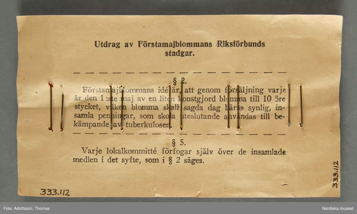 Majblomskarta med 1929 års majblommor.
Röd  karta av rektangulärt papper med tryckt text "FÖRSTAMAJBLOMMANS RIKSFÖRBUND. Säljes till bekämpande av Tuberkulosen. Bär ej blomman före Valborgsmässoafton.10 st. blommor à 10 öre st." Handskrivet i blyerts på framsidan av kartan "-29". På kartan fästa 10 st majblommor av celluloid med dubbla kronblad i gult med röd mittknopp av glas och nål av gulmetall.
På baksidan tryckt text: "Utdrag ur Förstamajblommans Riksförbunds stadgar." + hela pararapraf 2 och 5.
Lena Kättström Höök/ 2013-04-22

Vid försäljningen var majblommorna fästade på detta sätt.
/Lena Kättström Höök 2008-11-17