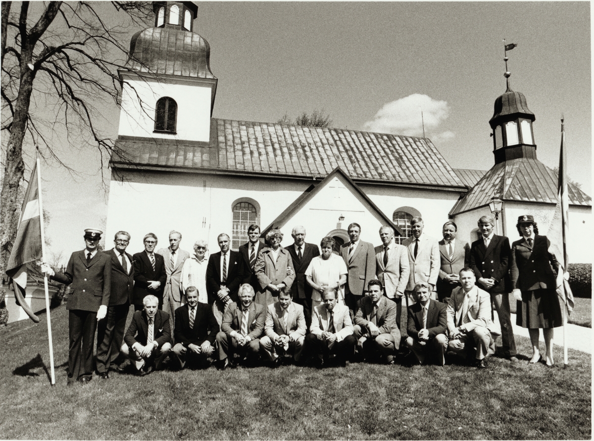 Trafikaktiebolaget Grängesberg - Oxelösunds Järnvägar, TGOJ-dagen. Deltagare som fick guldur tillsammans med fanbärare och TGOJ-chefen Ragne Johanson utanför Husby-Rekarne kyrka. De guldursmottagare som vi vet är på bilden heter; Maj-Britt Eriksson, Sven Israelsson, Kjell-Åke Karlsson, Bengt Lager, Viola Persson-Kärr, Brita Ranégie och Leif Rehnberg.