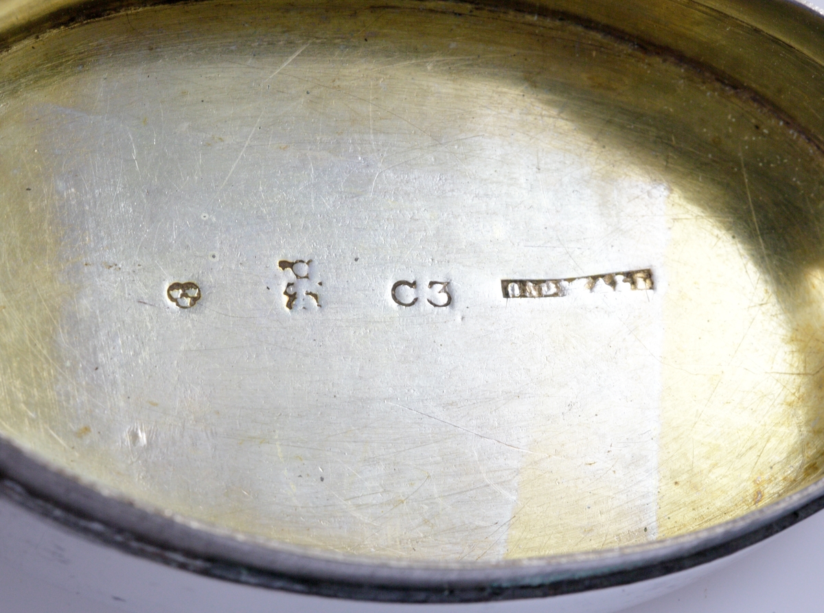 Dosa, silver.
Oval, slät modell. Invändigt förgylld. Ägarinitialer: "J.O.D." på dosans undersida. 
Stämplar (något otydliga) på lockets undersida.