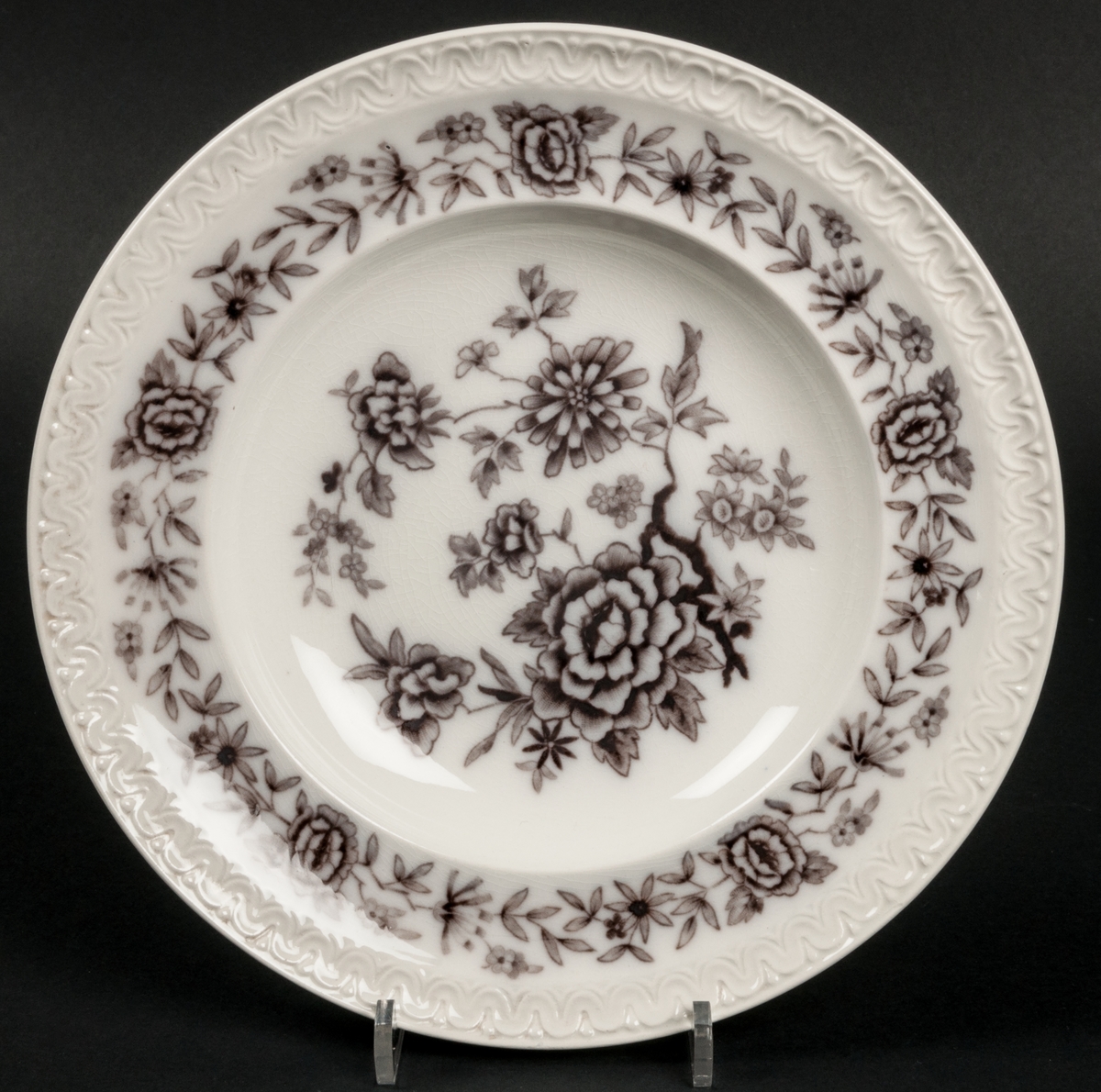 Djup tallrik, modell AS, dekor Stjärnsund. Koppargravyrtryck i mullbärsbrunt.
Vit massa med brun dekor av blomster.
Bård i godset längs brämet.