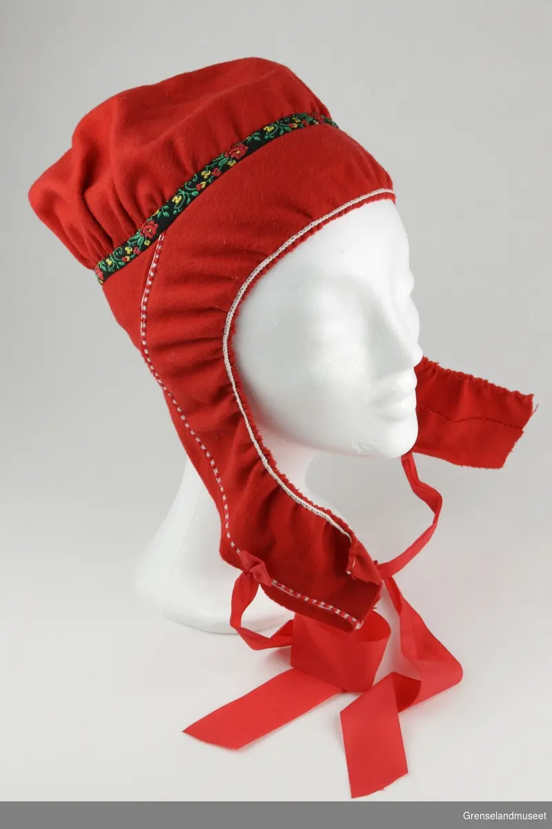 Samisk kvinnelue. Rødt klede med pyntebånd.