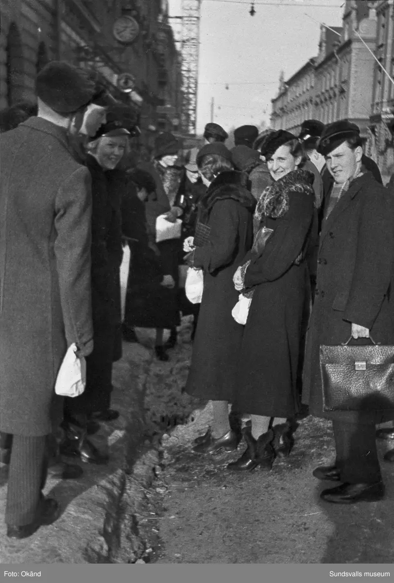 "Studentexamen 1937 vid Sundsvalls högre läroverk började med svensk skrivning. Innan vi gick till skolan samlades vi vid Bewe's hörna (Storgatan-Torggatan). Där släppte var och en av oss en ettöring från födelseåret ner i dagvattenbrunnen. Därefter gick vi till skolan med en fot i rännstenen och den andra på trottoaren så lång det gick." Bild 2 Fr v Lennart Uhlin, Ture Engblom och Martin Löfgren. Bild 6 Betygen studeras. Fr v Liljekvist, Curt Stål, L M Thuresson samt okänd. Bild 8 Numrerade personer. 1. okänd 2. L. H. Thuresson 3. okänd 4. Thure Engblom 5. okänd 6. Martin Löfgren 7. Lundgren (?) 8. Curt Stål 9. G-A Wahlsten 10. Ingemar Flodén 11. Anna-Lisa ? 12. Nilsson (lärare) 13. Maidi Budde 14. Lennart Uhlin 15. Harald Schibbye. 
Bilder ur fotoalbum som tillhört G A Wahlsten.