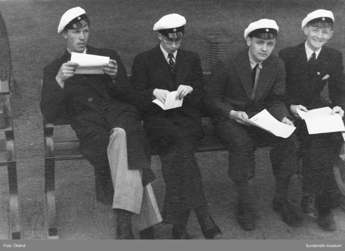 "Studentexamen 1937 vid Sundsvalls högre läroverk började med svensk skrivning. Innan vi gick till skolan samlades vi vid Bewe's hörna (Storgatan-Torggatan). Där släppte var och en av oss en ettöring från födelseåret ner i dagvattenbrunnen. Därefter gick vi till skolan med en fot i rännstenen och den andra på trottoaren så lång det gick." Bild 2 Fr v Lennart Uhlin, Ture Engblom och Martin Löfgren. Bild 6 Betygen studeras. Fr v Liljekvist, Curt Stål, L M Thuresson samt okänd. Bild 8 Numrerade personer. 1. okänd 2. L. H. Thuresson 3. okänd 4. Thure Engblom 5. okänd 6. Martin Löfgren 7. Lundgren (?) 8. Curt Stål 9. G-A Wahlsten 10. Ingemar Flodén 11. Anna-Lisa ? 12. Nilsson (lärare) 13. Maidi Budde 14. Lennart Uhlin 15. Harald Schibbye. 
Bilder ur fotoalbum som tillhört G A Wahlsten.
