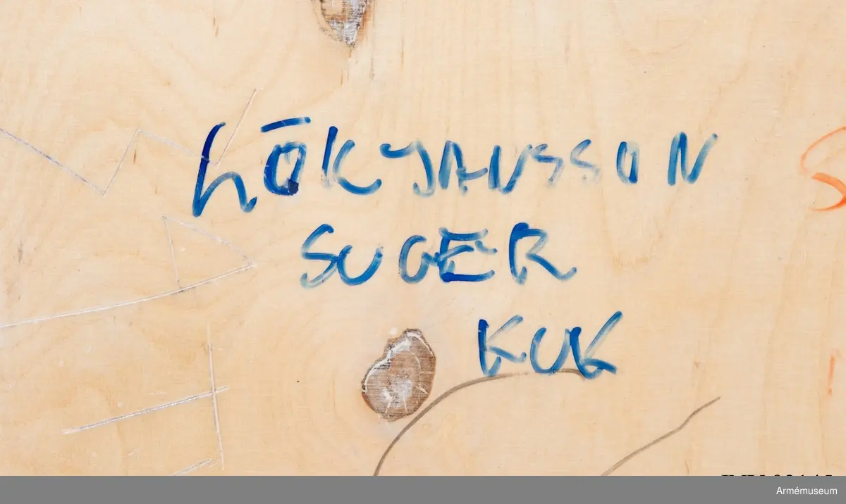 Sängbotten i trä avsedd för våningssäng i metall. Nedklottrad med text och bilder av mestadels sexistisk karaktär. Flera personer har använt ytan för att räkna ned veckorna och dagarna fram till muck.