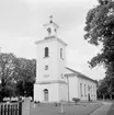 Den nya kyrkan i Vallerstad kunde invigas den 1 december 1833. Byggnadens uppfördes på grunden av en äldre, tidigmedeltida kyrka. I Vallerstad valde man det lite udda greppet att anläggna den nya kyrkans grund runt den äldre kyrkobyggnaden innan den vidare revs. På så vis blev störningen av sockenbornas kyrkogång förkortad i tid . Vallerstad kyrka var den blivande storbyggmästaren Abraham Nyströms första kyrkobyggnad att ansvara för. Här dokumenterad av Östergötlands museum 1978.