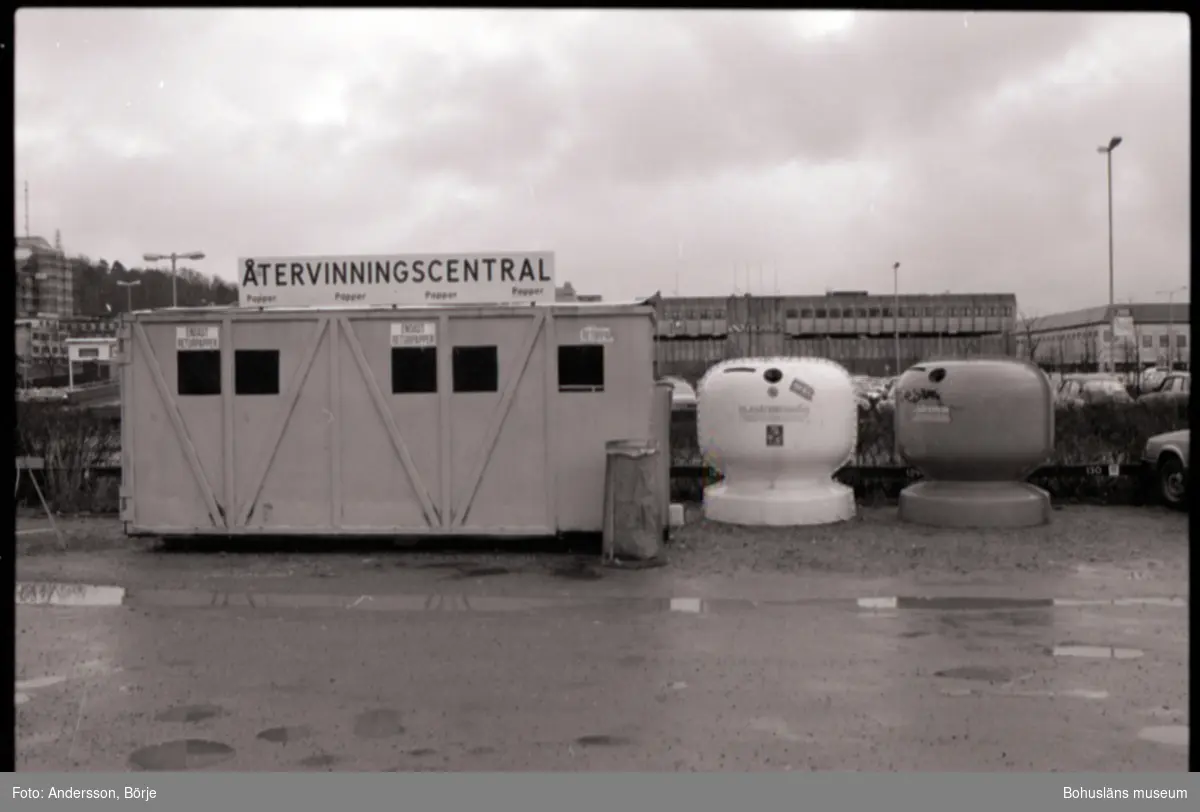 Dokumentation av en återvinningscentral vid Kampenhof i Uddevalla, i bilden syns containrar för glas och papper. Personer lämnar sitt avfall i dessa. 