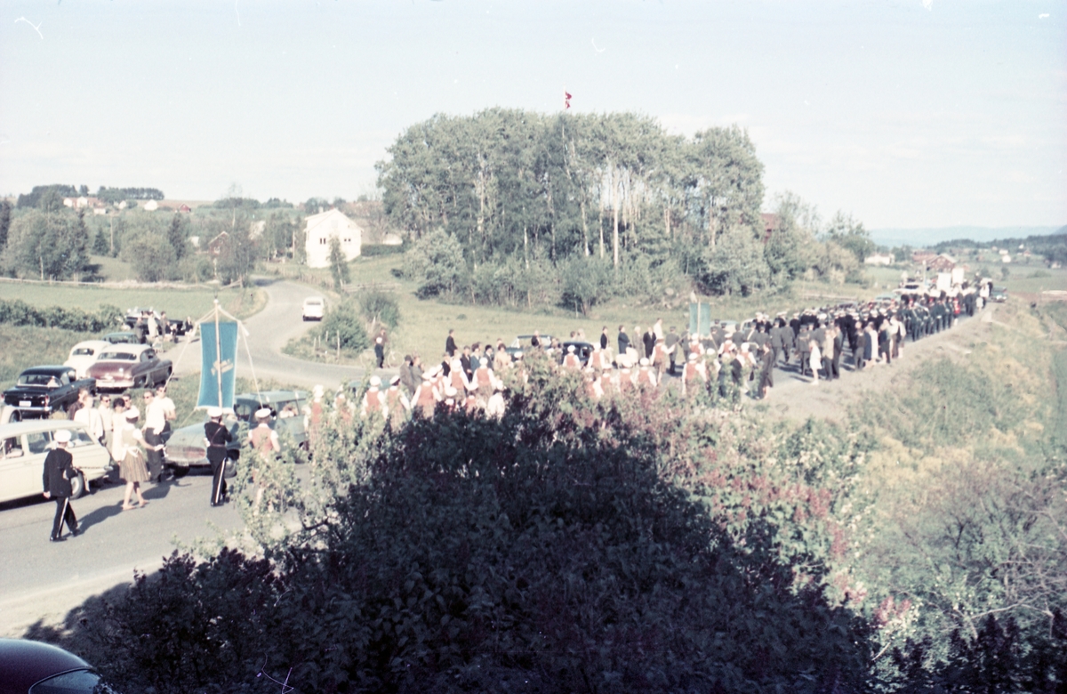 Serie på 16 bilder trolig fra Sangens og Musikkens Dag i Østre Toten, muligens 1961. Bildene er tatt i retning Brunsberg fra fotografens eiendom Odberg på Kraby, der forskjellige korps og kor deffilerer forbi.