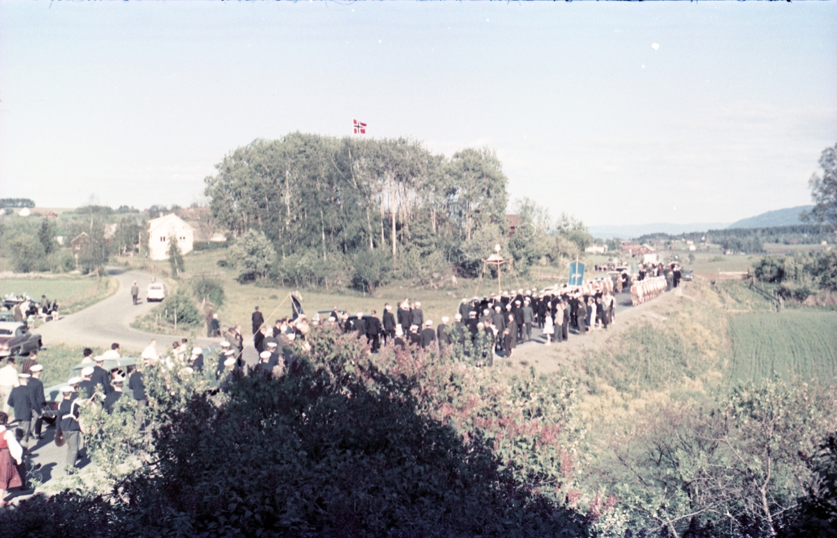 Serie på 16 bilder trolig fra Sangens og Musikkens Dag i Østre Toten, muligens 1961. Bildene er tatt i retning Brunsberg fra fotografens eiendom Odberg på Kraby, der forskjellige korps og kor deffilerer forbi.