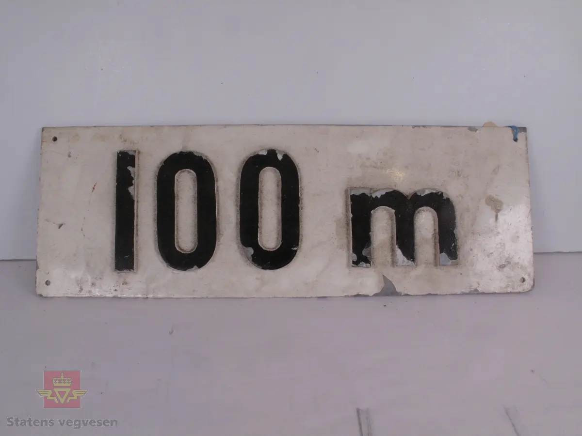 Skiltet er i metall, med tegnene i relieff. Disse står ca 0, 5 centimeter ut fra skiltet. Det er opprinnelig malt hvitt, men malingen har skallet av flere steder. Tegnene har vært svarte. Det er fire skruehull, et i hvert hjørne.
