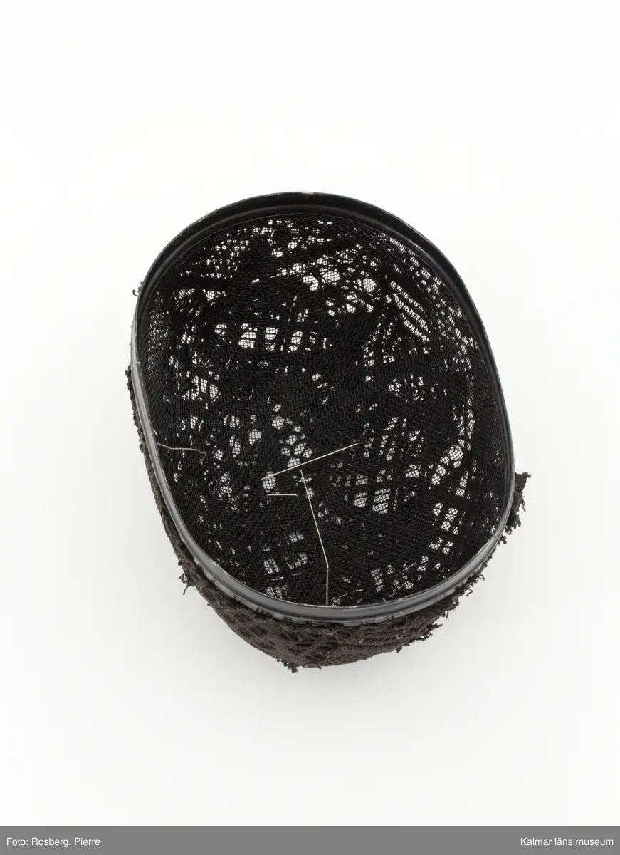 Svart oval fäktarmask med broderade ansiktsdrag i vitt.
