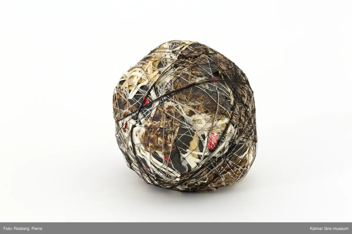 Tredimensionellt konstverk i form av ett klot, bestående av olika material och lindat.