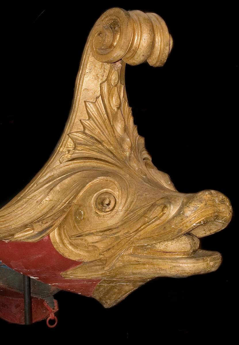 In 1783 King Gustaf III travelled to Italy. In Venice he was taken on a tour in a gold-ornamented gallery. The king also watched a splendid spectacle in the form of a regatta on the Canal Grande. A great number of decorated boats and gondolas assembled well before noon. At two o'clock in the afternoon boats with Venetian nobelmen came to pick up the king and his entourage to see the regatta. The boats were decorated with silk, canopies, parasols and flowers. The rowers were dressed in silk and adorned with silver. "The spectacel was vivid, full of splendor and distinctive character and quite dazzling", as Gundmund Jöran Adlerbeth writes in his diary from the journet. King Gustav III was very much impressed.

I order to supreise the king, master ship builder Fredrik Henrik af Chapman had "two pleasure vessels for Haga" built. Haga was a rural ground, north of Stockholm, where Gustav III at the time was creating a royal rank park. The "gondolas" were probably built in 1785 or 1786, and the heads of the boats were in all certainty made by the sculptor Hohan Törnström.

The king was "infinitley pleased", and the sloops came to be used frequently on the Brunnsviken and off Drottningholm. For rowing, boatsmen commandeered from the navy were used. The boar have been called sloops, pleasure vessels or gondolas depending on where they mentioned. The shields were originally 24 in number, with motifs from antiquity and from the twelve labors of Heracles.

After the assassination of Gustav III the sloops were forgotten and rarley used until they were pun into service again for a while during the reign of Karl XV (1859-1872). Since then, they have been stored at various places, e g near the copper tents at Haga, on Skeppsholmen and, since 1966, in the collections of the National Maritime Museum.    