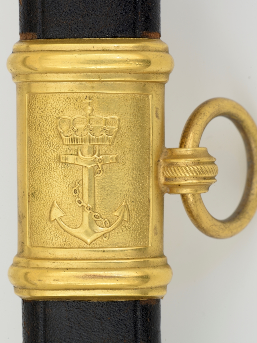 Norsk marinesabel Modell 1842. Feste i forgyllyt messing. Flat knapp med blomstermotiv. Nakkestykke merket "Lars Yggeseth"
Hvitt plastgrep med riller med snodd messingtråd i rillene. Gjennombrutt parerplate på utsiden med urent anker..Bakre parerstang svakt medbøyd og ender i en flattykt kule. Fremre parerstang går over i håndbøylen.
Gulltråde portepé flettet med alternativt svart/mørkeblått og gull.
Svakt krummet enegget klinge med rygg- og midtstillt blodrand. Klingen har etset dekor med moderne marinefartøy og kronet urent anker. Klimgen er merket med Carl Eichorns Solingenstempep i en oval rundt et ekorn.
Lærbalg med forgyllte messingbeslag. Munnblikket merket med norsk løve på forsiden og " Y " på baksiden. Midtbåndet er merket med kronet urent anker. Doppskoen har Neptuns tref ork og militære attributter.