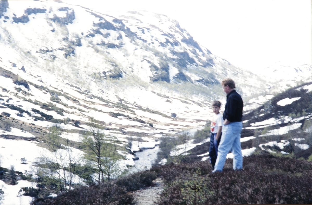 Mann og gut ser utover snødekka heielandskap
