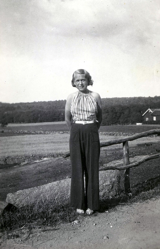 Inga Lill Dahlberg Börjesson från Burås i Göteborg (1915 - 2002) står på en landsväg i Tulebo. Sommargäst hos Fredrikssons och Nilssons.
Till höger skymtar uthusen (sommarbostäder) hos Oskar Fredriksson.