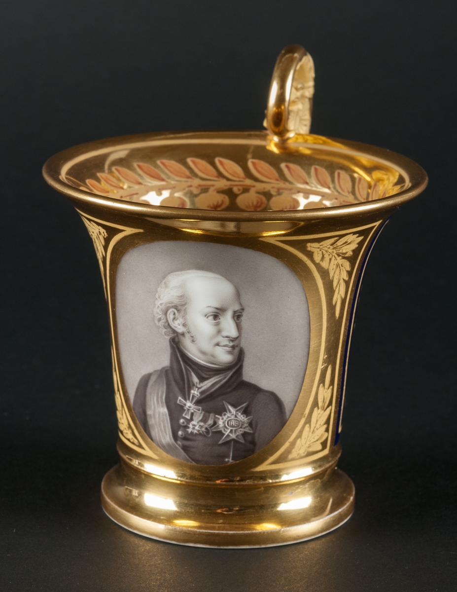 Karl XIII:S kopp.
Kopp med fat från Daite Freies i Paris, omkring 1800.
Koppens höjd 9.5 cm. Fatets diameter 16,5 cm.
Koppen bär på ena sidan Karl XIII:s bild och är på motstående sida dekorerad med ett par antika hjälmar.
Dekor i empirestil i guld och blått.
En grepe med örnhuvud och palmettdekor. Fatet är dekorerat med en eklövskrans.