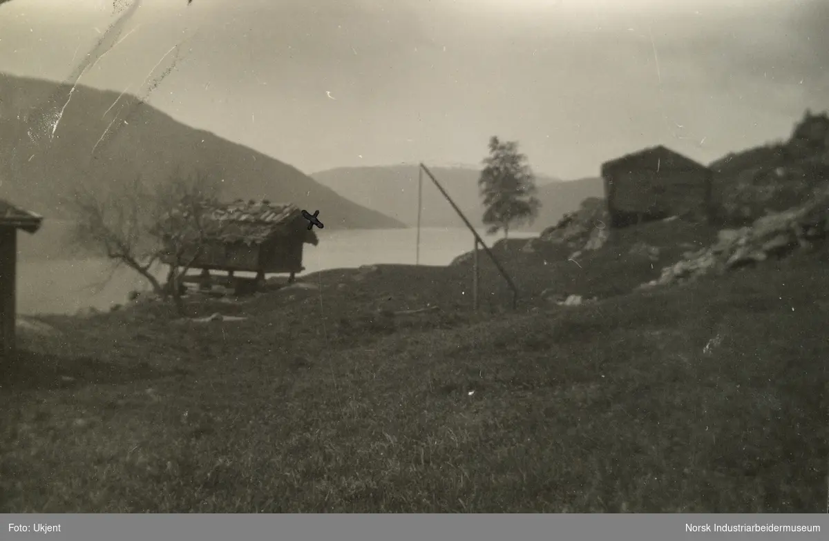 Laftet gårdshus og stabbur ved innsjø og fjell