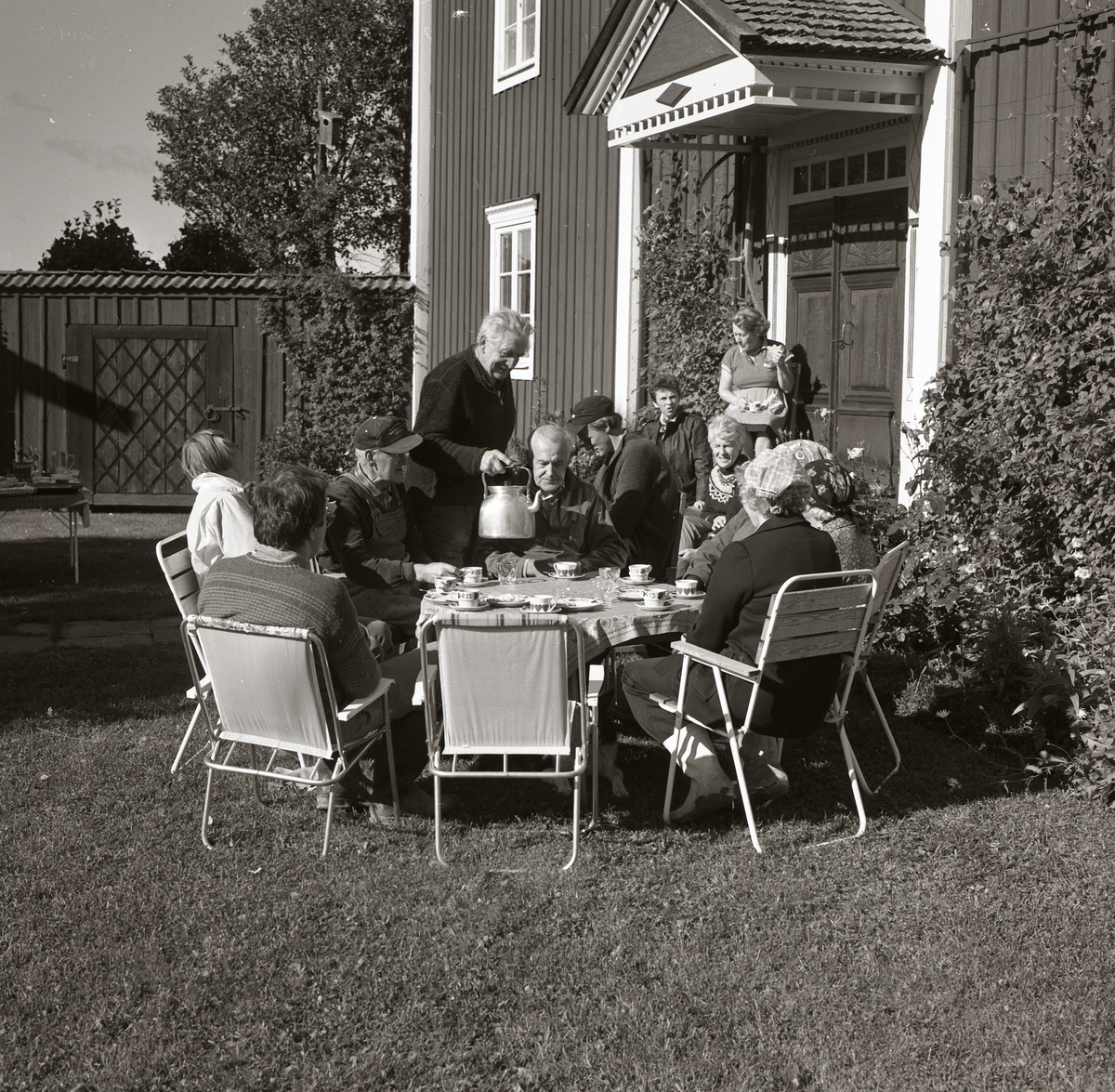 En grupp människor sitter runt ett bord och tar en fikapaus vid gården Sunnanåker den 21 september 1985.