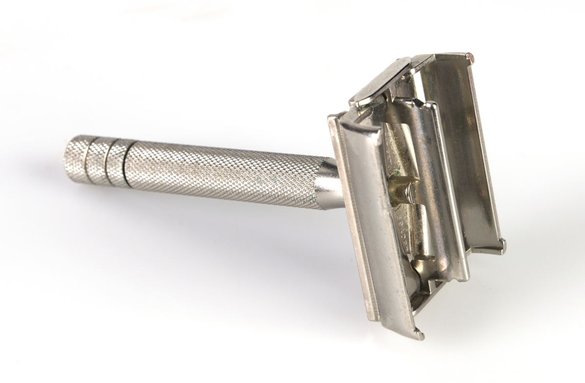 En barberhøvel i eske produsert av Gillette. Høvelen er laget av metall. Håndtaket er støpt slik at det er ruglete for godt grep. For å åpne/lukke høvelen skrur man nederst på håndtaket. Skrur man mot høyre åpnes den og man kan sette inn barberblad. For å lukke den skrur man mot venstre. Esken er laget av plast. Den nederste delen er rød og har et stativ som høvelen skal ligge i. Under er det et rom for å legge barberblader i. Lokket er av blank plast og er hengslet fast. På både høvel og eske er det stempel, se "Påført tekst/merker".