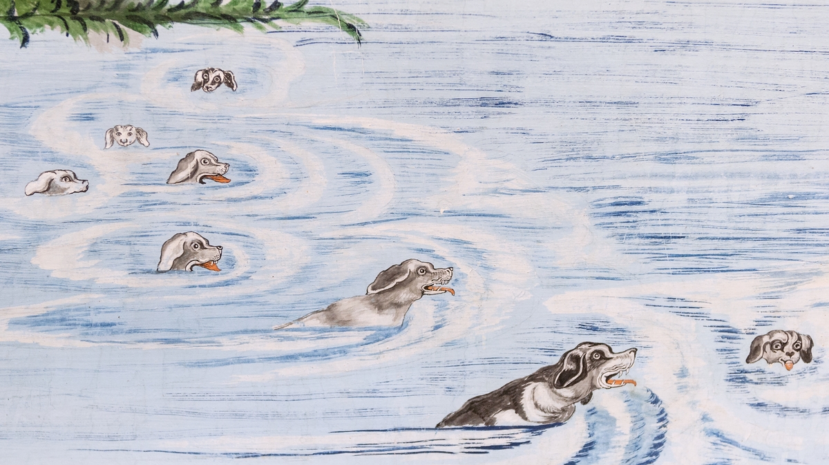 Del av väggmålning. Limfärg på papp. Två pilastrar och målat väggfält. Jaktscen med hundar som förföljer en hjort samt man till häst på berghällar i bakgrunden.