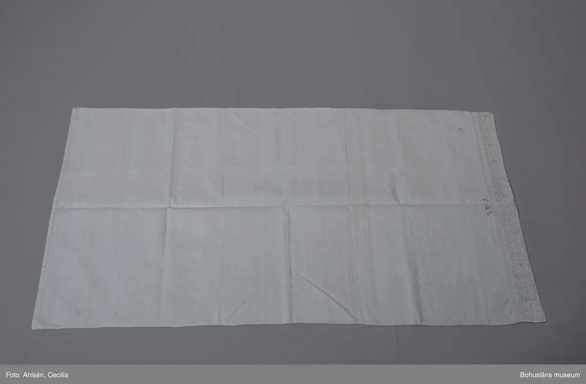Långörngott av vit handvävd linnelärft, vådbredd 65,5 cm. Sydd (handsydd) som en avlång påse med öppning i ena kortsidan och en infällt hålsömsbroderi i den andra. Mitt inunder spetsen märkt med A N I S 1889 i korsstygn med rött bomullsgarn. Den 6 cm breda spetsen är sydd i vitt lingarn direkt i väven i utskårssöm, en hålsöm med utskurna hål. Mönstret bildar åttuddiga stjärnor. Partiet är sedan dubbelvikt och fastsydd vid örngottets stadkant med kastsöm.