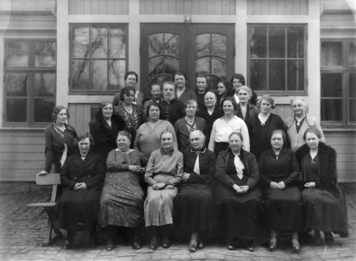 Kooperativa Kvinnogillet i Varberg samlat utanför en glasveranda. Kvinnogillet startade år 1912, efter ett tal av Josefina Rosvald i Göteborg, och dess första ordförande var Gerda Persson. När fotot togs var Mary Svensson ordförande (1924-1945). Se även foto nr GB1_247.
Personer på bilden, utan ordning: Mary Svensson, Elsa Sjöberg, Selma Andersson, Selma Karlsson, Klara Karlsson, Astrid Hendberg, Karin Mossberg, Elina Bartholtsson, Anna Eliasson, Gunborg Hansson, Josefina Olsson, Alvina Sedergren, Katrin Hagström, "Lolles mamma", Svensson.