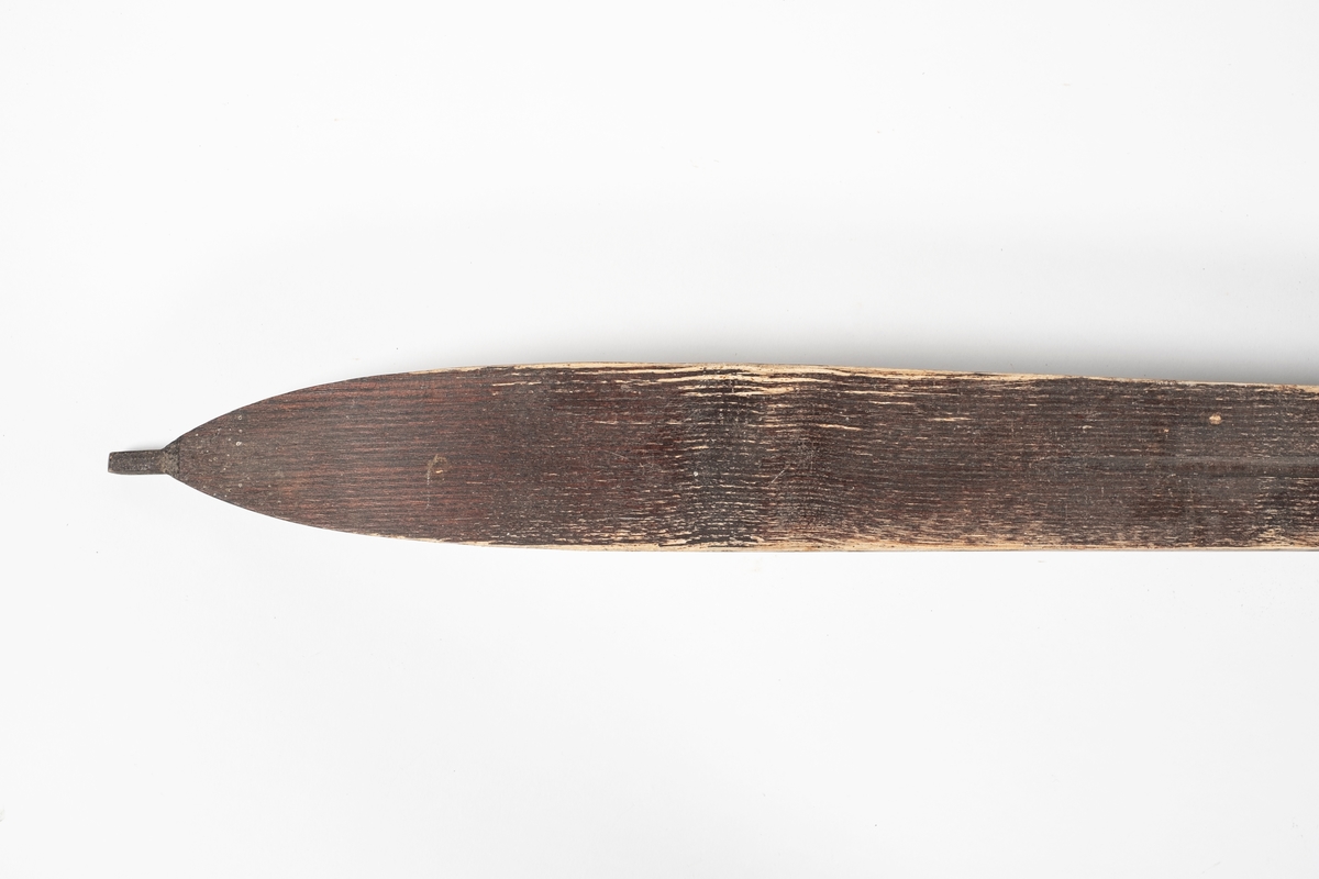 Ski med jevn bredde, svinger litt inn på midten. På midten av skien er det en forhøyning med påspikret plate som forsterkning. Bindingen består av lærremmer over tær og vrist, og bak hælen. Remmene er festet til en bøyd jernplate, som er festet i en spalte i skien, under forsterkningen. Skien er rett bak og spiss foran. Skien krummer oppover foran, og har en liten tapp ytterst. Under skien er det en renne i midten. Det er utskåret striper langs oversiden av skien som dekorasjon.