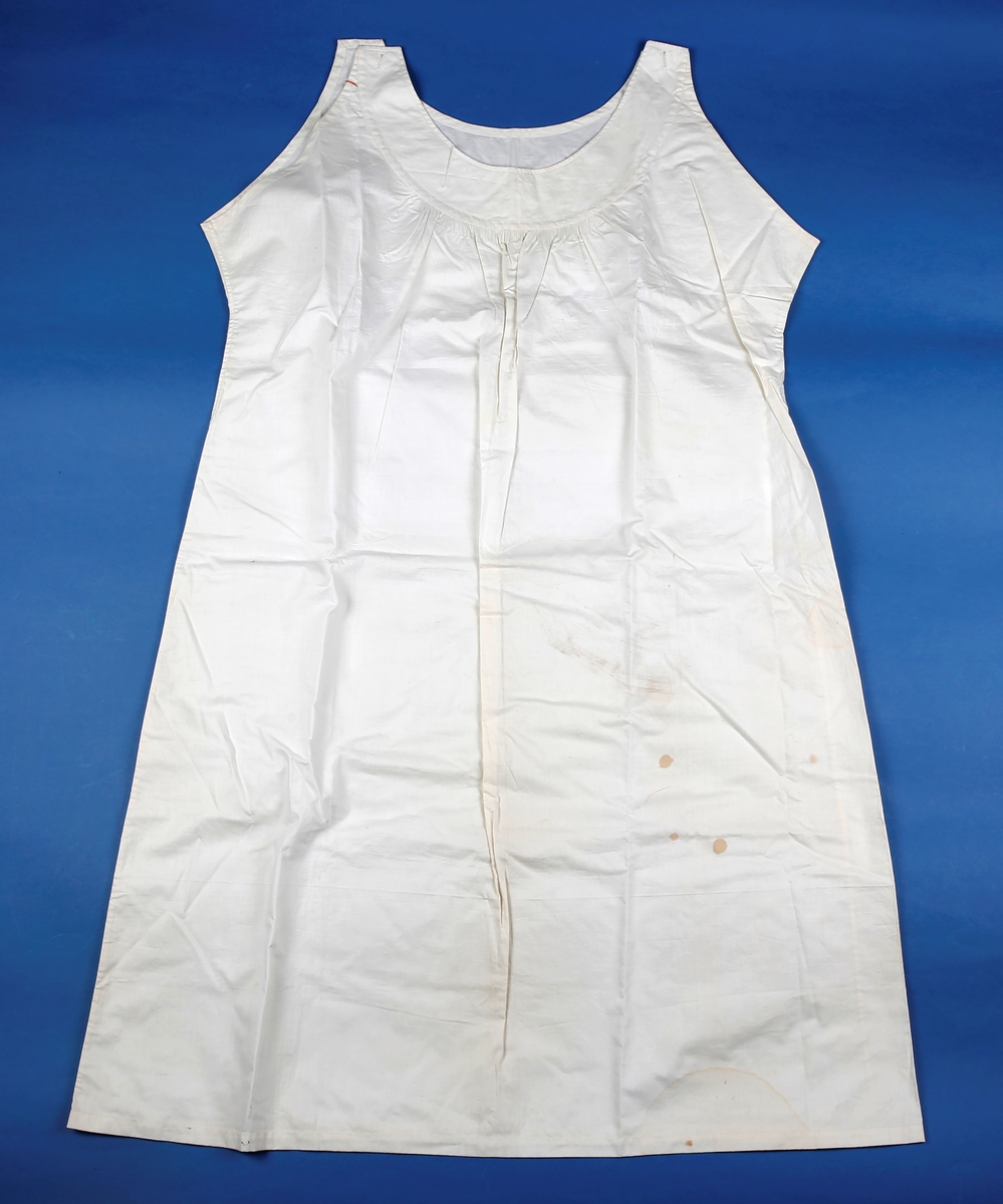 Ganske langt linnet som kneppes på skuldrene. Belegg sydd rundt ermhull og halsringing. Belegget er bredere foran hvor det er sydd stikninger. Stoffet er stripet under belegget foran. Belegg, opplegg og indresømmer er sydd ned for hånd.