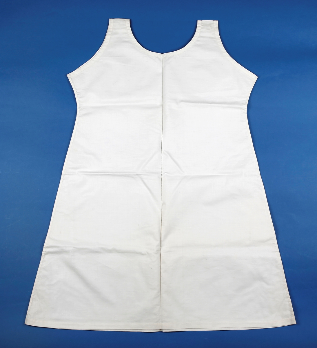 Enkelt linnet der framstykke og bakstykke er like. Sydd sammen på maskin med indresømmer, opplegg og nedsying av belegg i halsen og rundt ermhull sydd ned for hånd. 