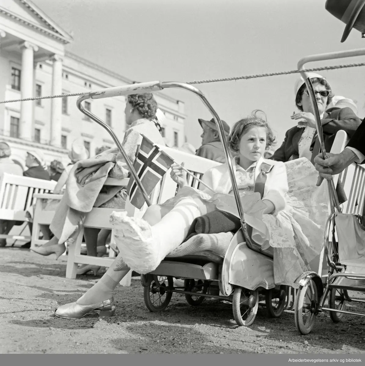 Jente med gipset ben ser på barnetoget. 17. mai 1960