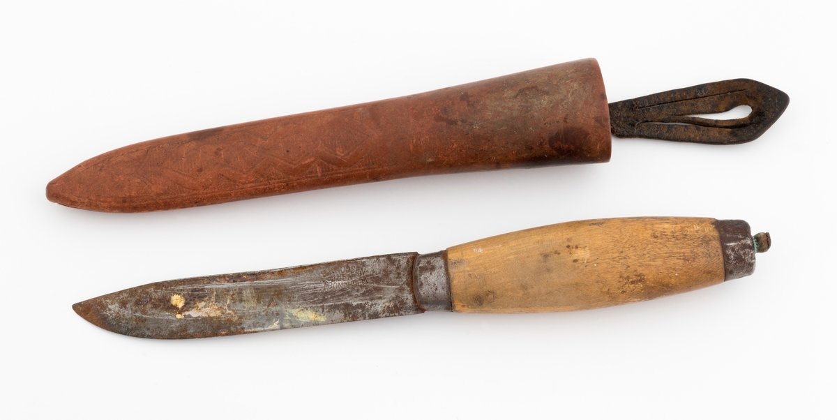 Tollekniv med slire, produsert av B. Knudsen på Ila i Trondheim. Kniven er 22,3 centimeter lang fra spissen av bladet til knappen i den bakre enden av skaftet. Bladet er 11,1 centimeter langt og snaut 2,1 centimeter bredt ved brystningen innerst mot skaftet. Bladet var opprinnelig snaut 3 millimeter tjukt, men bladryggen har slagmerker som har gjort den noe bredere. Sannsynligvis har dette skjedd fordi eieren har slått på knivnakken med et slagredskap for å kunne kløyve stikker som skulle brukes under opptenning. Den venstre sida av knivbladet bære smedstempelet «B. KNUDSEN  ILEN  TRONDHJEM». 

Kniven har et 10,8 centimeter langt treskaft med cirka 1 centimeter brede holker i begge ender. I den bakre enden er det en cirka 5 millimeter høy knopp med skråslipt endeflate. Treskaftet har en konveks form og et ovalt tverrsnitt. Midtpartiet måler 2,9 X 2,2 centimeter. Skaftet er ikke innsatt med noe fargestoff, men det kan ha vært oljet.

Slira er 18,2 centimeter lang, men har i tillegg en lærstropp for feste i en knapp i bukselinninga, slik at total lengde blir 24,6 centimeter. Sliras hoveddel er lagd av brunlig papp og holdes sammen av en søm langs det som var midtaksen av sliras bakside. Forsida av den delen av slira som omgav knivbladet har et siksak-mønster med litt skravur.

Knivmakerne Broder Knudsen (1886-1967) og Bård Knudsen bodde i Trondheim. Det er sannsynlig at en av disse har produsert denne kniven.