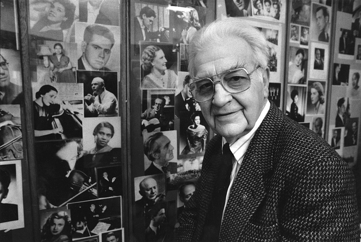 Bilde av Olaf T. Ranum junior foran "kunstnerveggen" sin, med signerte foto av ulike artister som har gjestet Ranum.