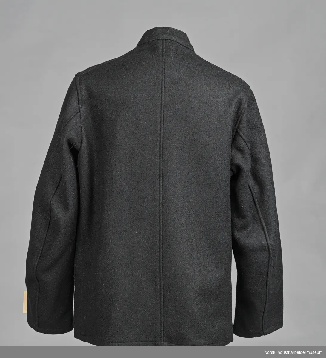 Sort arbeidsdress (jakke og bukse) med sorte blanke knapper.