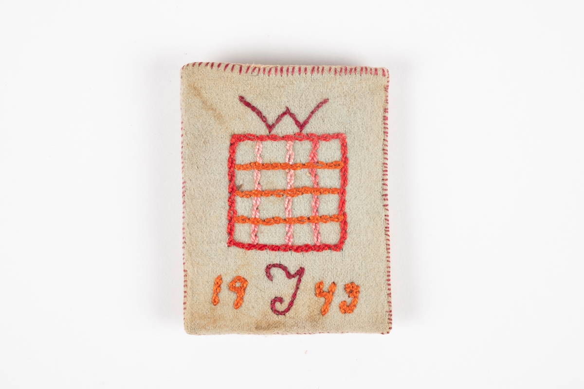 En liten firkantet lomme laget av papp kledd med tekstil. Inne i lommen er det en papirlapp. Det er brodert ruter med årstall under på den ene siden og et hjerte med bokstaver i på den andre.