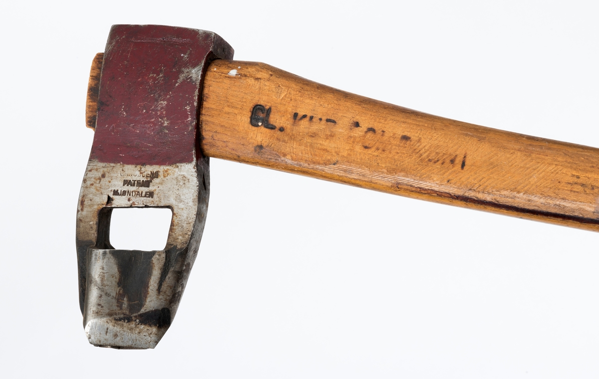 Øks - brukt til merking av fløtingstømmer i målings- og annammingsprosessen som foregikk langs vassdragene i overgangsfasen mellom vinter og vår, da tømmerstokkene etter måling formelt skiftet eier - fra skogeieren som hadde organisert hogst og framkjøring til sagbruk eller treforedlingsbedrift, som kjøpte tømmeret med sikte på videre bearbeiding til produkter som var salgbare på et større marked. 

Øksehodet (den smidde delen) er 16,3 centimeter høyt fra eggpartiet til nakken. Nakkedelen er 6,0 centimeter lang og om lag 2,6 centimeter bred. «Kjakene» - sideveggene rundt «øyet» (skafthullet) – er forholdsvis rette. På den nedre delen av øksebladet er det en U-formet utsparing, og til endestavene (Knudsen-smedene kalte dem «stabler») er det påsveiset en cirka 4,6 centimeter høy fasslipt, profilegget «sko». Eggprofilen er en trekant med en halvsirkelformet utbuktning på ei av sideflatene. Dette symbolet ble altså slått inn i yteveden på fløtingstømmeret, som tegn på hvem som eide stokkene. Den øvre delen av øksehodet er lakkert med rød lakk. På venstre side av dette øksebladet (sett i øksebrukerens perspektiv) finner vi smedstempelet «K. KNUDSEN  PATENT  MJØNDALEN». Smeden Karl Henrik Knudsen (1870-1956) tok patent på denne typen merkeøkser i 1908.

Øksa har et 60 centimeter langt og forholdsvis rett treskaft (sannsynligvis ask eller hickory). Som økseskaft flest er det bredest i høyderetningen og smalest i bredderetningen i den fremre enden, og mer rundovalt bakerst. Den fremre enden av skaftet er kilet med en trekile som skulle redusere faren for at øksa løsnet fra skaftet under merkingsarbeidet. Den venstre skaftsida har vært påført et navn ved hjelp av et svijernstempel.  Navnet er imidlertid forsøkt fjernet ved hjelp av ei rasp, antakelig fordi det firmaet som opprinnelig fikk tømmeret sitt merket med denne øksa ble avviklet, slik at merket muligens ble overtatt av en annen virksomhet. Det kan se ut til å ha stått «GL. KUR KOMPANI».

Litt generell informasjon om bruken av merkeøkser i skogbruket finnes under fanen «Opplysninger».