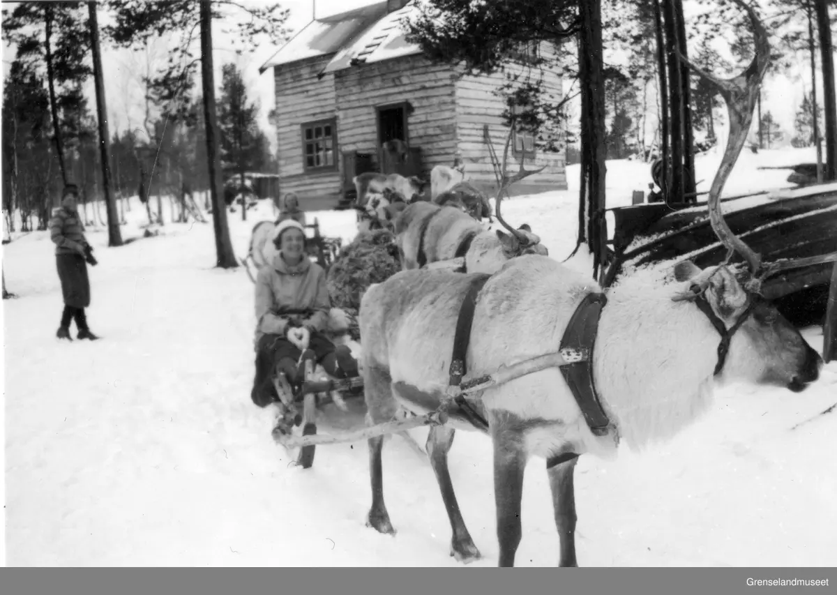 To kvinner på utfart fra en hytte, begge to på reinslede, Pasvik? En gutt står og ser på.