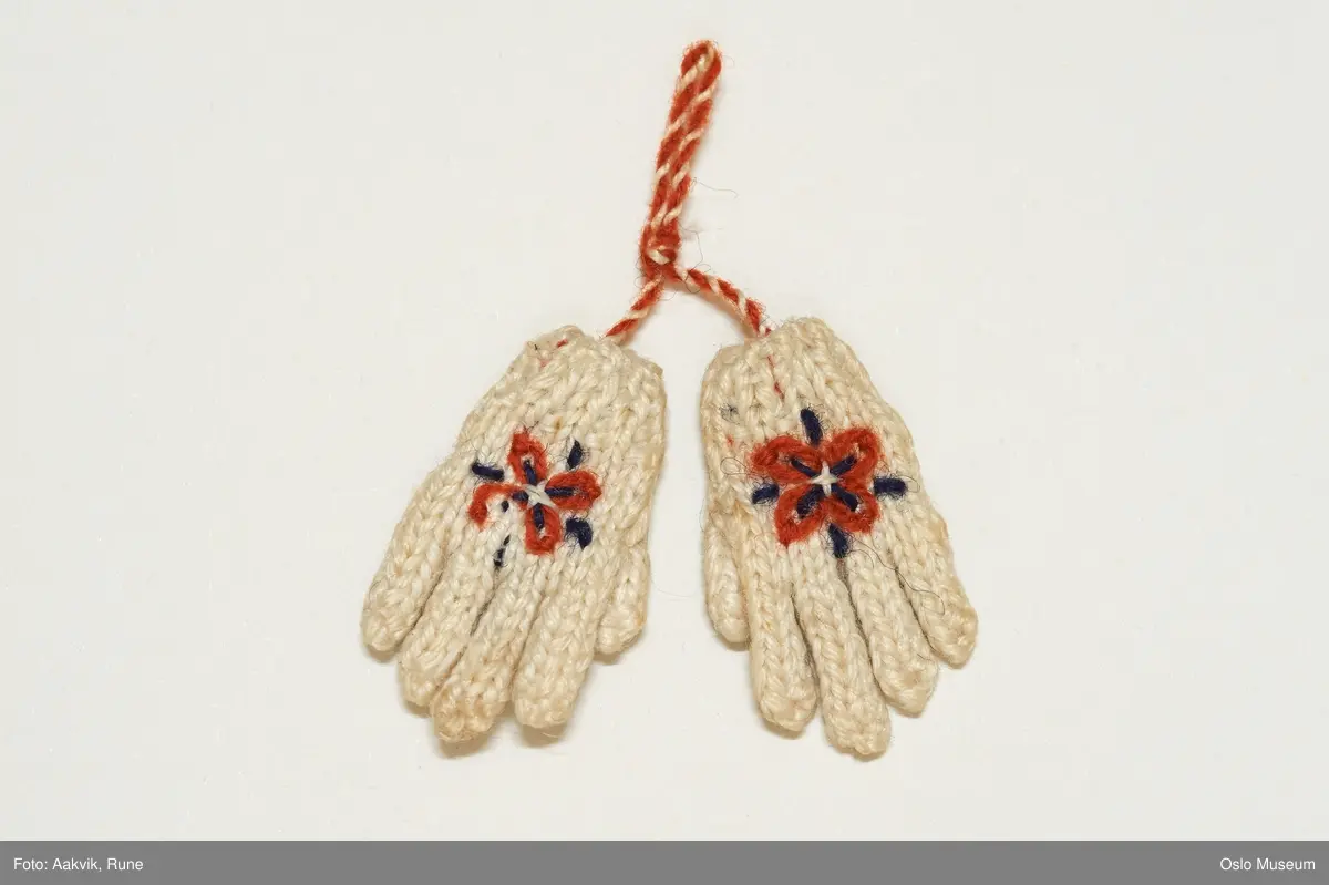 bittesmå hvite strikket votter med rosemønster og tekst