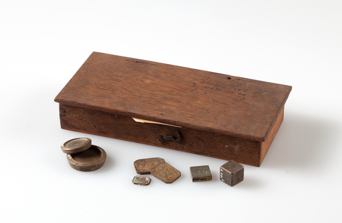 Skrin av tre (A) til vekt og lodd. Innholder: 
Håndvekt med 2 skåler (BD).
Lodd av ulik størrelse (EQ) og form.
Loddene er påført enheter i det gamle engelske medisinalvektsystemet.