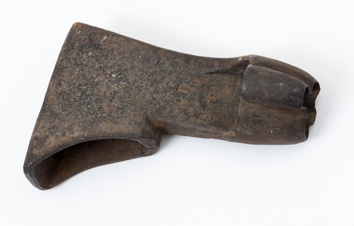 Øksehode – brukt til merking av fløtingstømmer i målings- og annammingsprosessen som foregikk langs vassdragene i overgangsfasen mellom vinter og vår, da tømmerstokkene etter måling formelt skiftet eier – fra skogeieren som hadde organisert hogst og framkjøring til sagbruk eller treforedlingsbedrift, som kjøpte tømmeret med sikte på videre bearbeiding til produkter som var salgbare på et større marked. 

Øksehodet (den smidde delen) er snaut 14,3 centimeter høyt fra eggpartiet til nakken. Nakkedelen er 9,0 centimeter lang og om lag 3,1 centimeter bred. «Kjakene» – sideveggene rundt «øyet» (skafthullet) – smalner mot den nedre delen av bladet. Det er en sprekk i godset i underkant av øyet. Nederst på bladet er det utsmidd en drøyt 3 centimeter høy fasslipt, profilegget «sko» (målet er tatt i ytterkant, der denne komponenten er smalest). Eggprofilen er formet som omrisset av en fugl med utspente vinger. Dette symbolet ble altså slått inn i yteveden på fløtingstømmeret, som tegn på hvem som eide stokkene. Øksehodet har ikke noe synlig smedstempel. Stålet er noe rustent. Bokstavene «OT» - antakelig smedens initialer - er antakelig smedens initialer.

Dette øksemerket ble ifølge merkekart for Glomma fra 1921 bruk til tømmer som ble innkjøpt på vegne av Lillestrøms Cellulosefabrik, en treforedlingsbedrift som var i virksomhet fra 1908 til 1943 (de første åra under navnet «Lillestrøm Sulfitfabrik»).

Litt generell informasjon om bruken av merkeøkser i skogbruket finnes under fanen «Opplysninger».