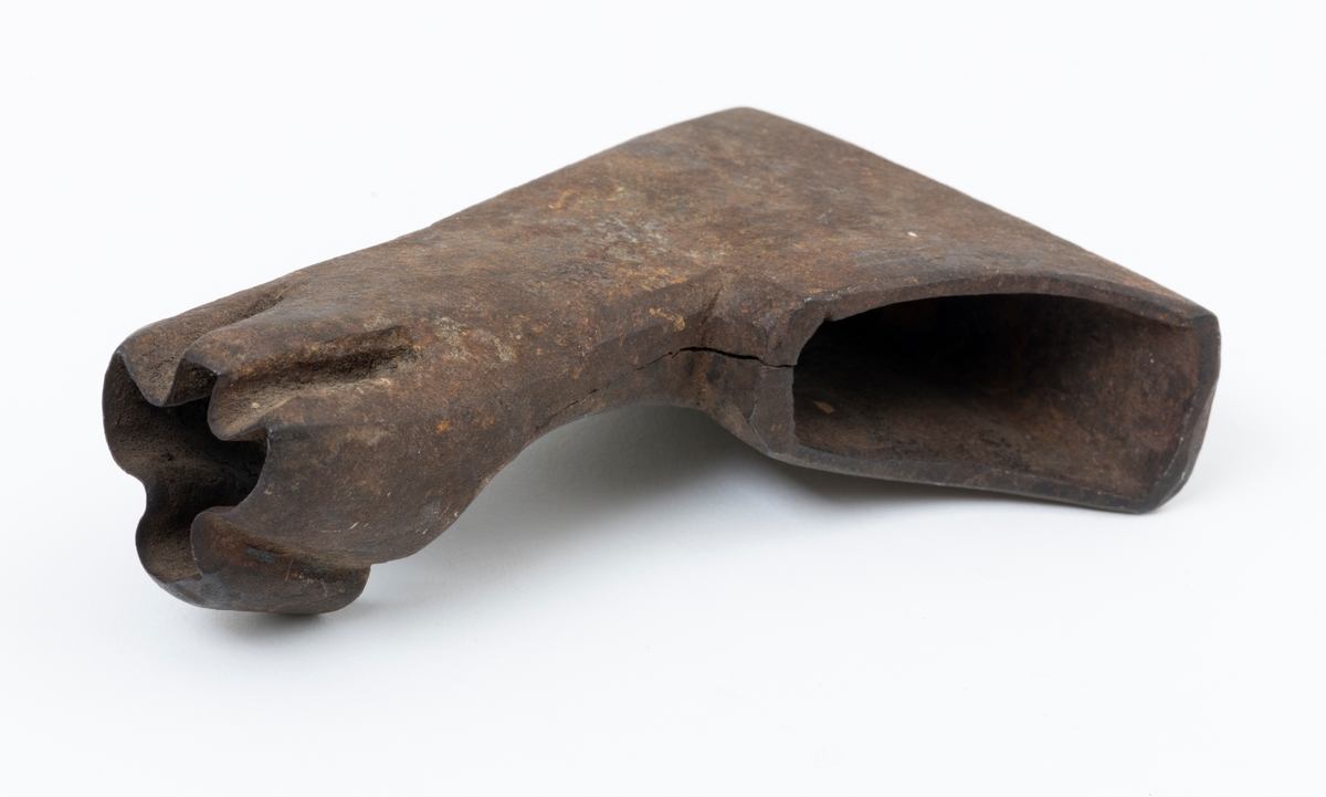 Øksehode – brukt til merking av fløtingstømmer i målings- og annammingsprosessen som foregikk langs vassdragene i overgangsfasen mellom vinter og vår, da tømmerstokkene etter måling formelt skiftet eier – fra skogeieren som hadde organisert hogst og framkjøring til sagbruk eller treforedlingsbedrift, som kjøpte tømmeret med sikte på videre bearbeiding til produkter som var salgbare på et større marked. 

Øksehodet (den smidde delen) er snaut 14,3 centimeter høyt fra eggpartiet til nakken. Nakkedelen er 9,0 centimeter lang og om lag 3,1 centimeter bred. «Kjakene» – sideveggene rundt «øyet» (skafthullet) – smalner mot den nedre delen av bladet. Det er en sprekk i godset i underkant av øyet. Nederst på bladet er det utsmidd en drøyt 3 centimeter høy fasslipt, profilegget «sko» (målet er tatt i ytterkant, der denne komponenten er smalest). Eggprofilen er formet som omrisset av en fugl med utspente vinger. Dette symbolet ble altså slått inn i yteveden på fløtingstømmeret, som tegn på hvem som eide stokkene. Øksehodet har ikke noe synlig smedstempel. Stålet er noe rustent. Bokstavene «OT» - antakelig smedens initialer - er antakelig smedens initialer.

Dette øksemerket ble ifølge merkekart for Glomma fra 1921 bruk til tømmer som ble innkjøpt på vegne av Lillestrøms Cellulosefabrik, en treforedlingsbedrift som var i virksomhet fra 1908 til 1943 (de første åra under navnet «Lillestrøm Sulfitfabrik»).

Litt generell informasjon om bruken av merkeøkser i skogbruket finnes under fanen «Opplysninger».